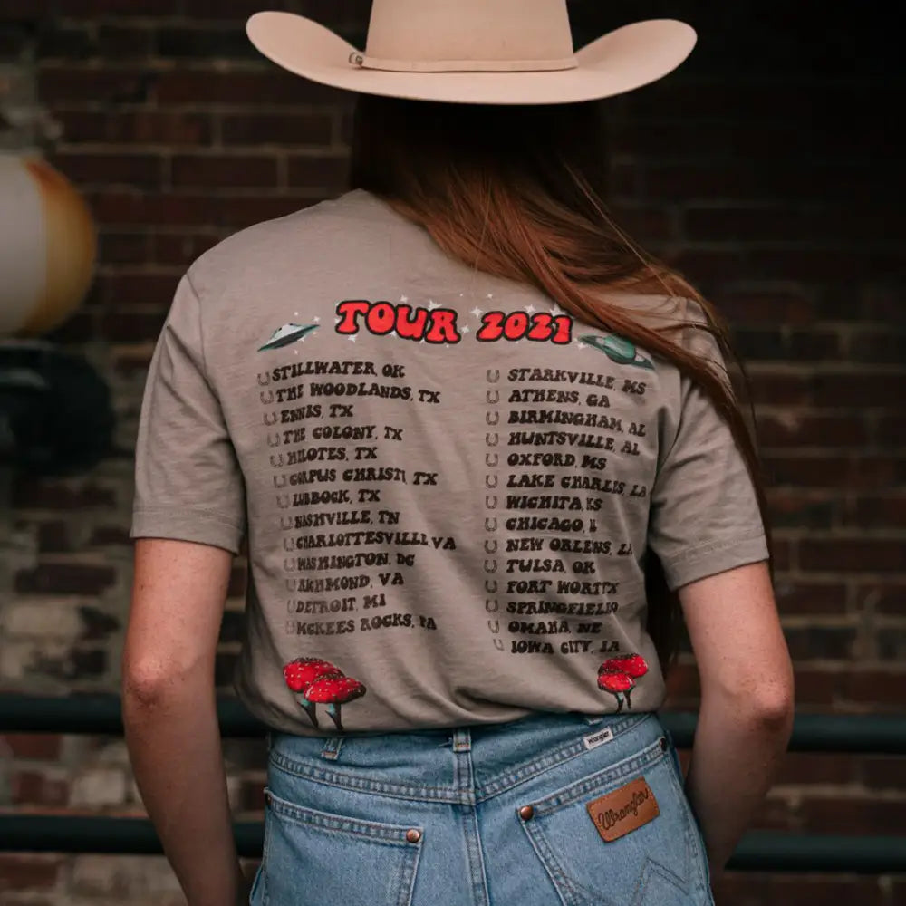 T-shirt displaying a tour schedule for 2023 with various city names listed.