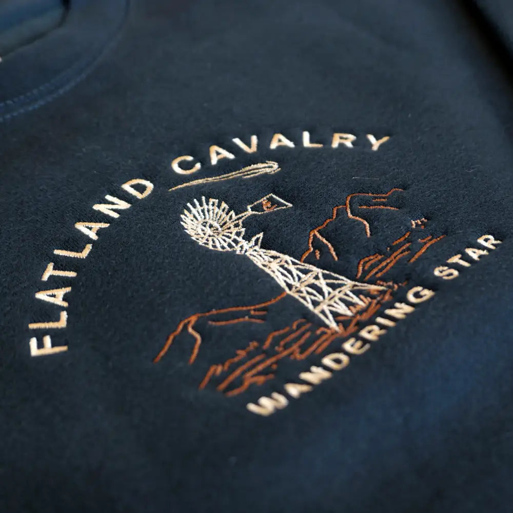 Embroidered logo featuring ’Flatland Cavalry’ text and a windmill design on dark fabric.