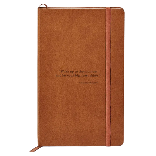 Brown leather-bound notebook with an elastic closure strap and an inspirational quote on the cover.