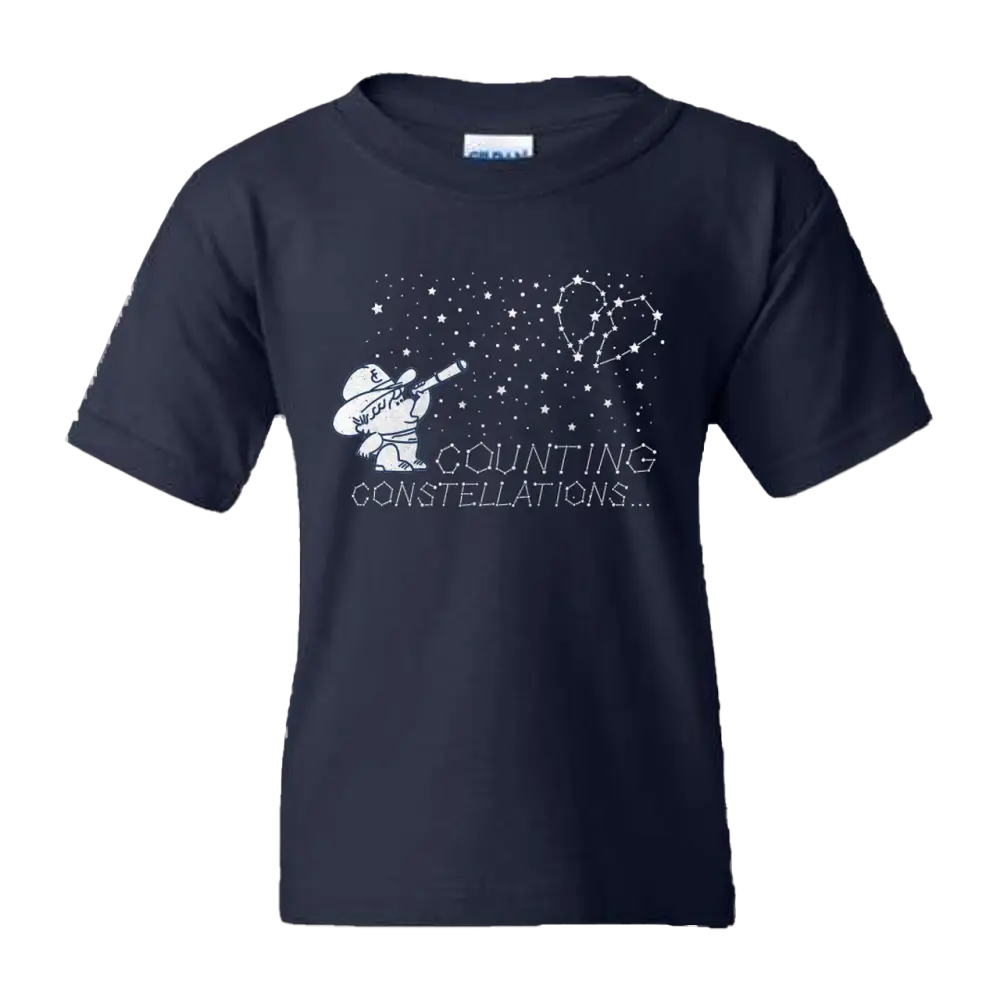 Navy blue kids’ t-shirt featuring a white graphic of a cartoon figure with a telescope pointing at a heart-shaped constellation, accompanied by the text ’counting constellations...’.